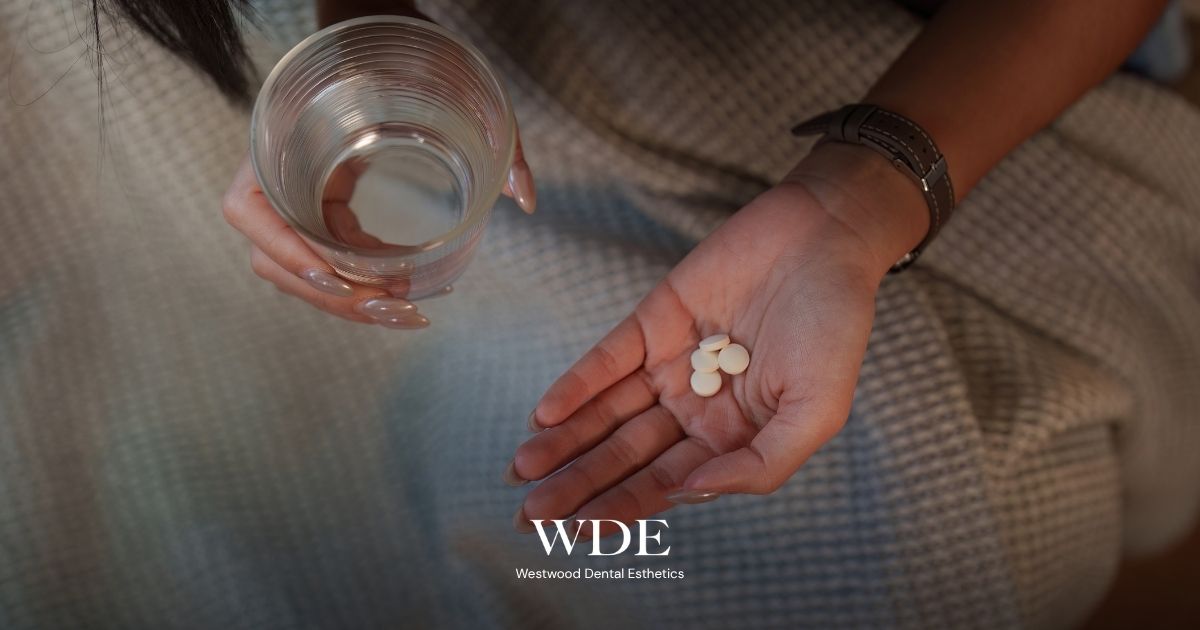 What to Do If You Crack a Tooth at Night: Step-by-Step Emergency Guide 4 Woman holding pain-relief tablets and a glass of water while managing discomfort from a damaged tooth before dental care.
