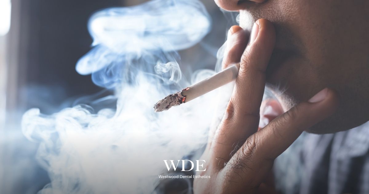Person smoking a cigarette, illustrating how smoking can affect healing, gum health, and the long-term success of dental implants